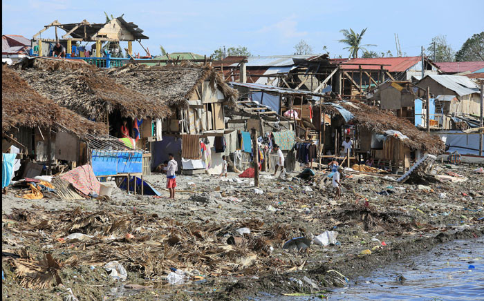 Residents stand next to their damaged houses with blown out roofs after typhoon Melor hit Bulan town, Sorsogon province, south of Manila on December 15, 2015. Tattered lanterns, festive lights and tin roofs littered towns in the central Philippines on December 15 after Typhoon Melor swept through, killing at least four people and leaving millions without power ahead of Christmas. AFP/Charism Sayat.