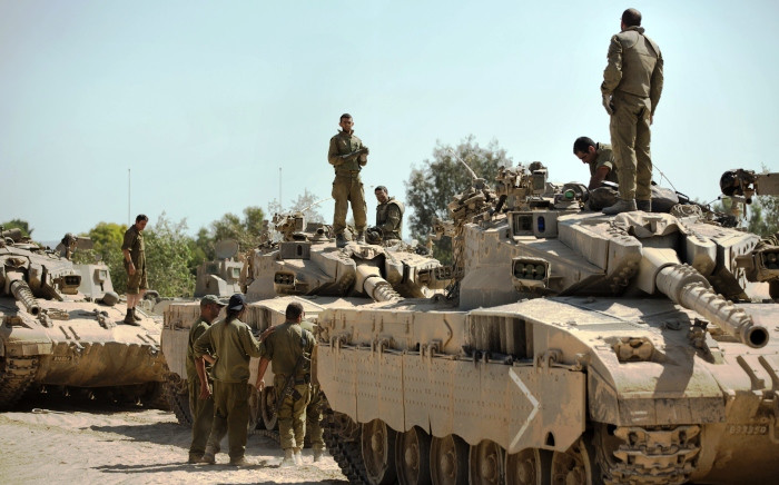 Israeli soldiers work on their Merkava tanks at an army deployment point near the Israeli-Gaza border on 20 August,2014. Picture: AFP.