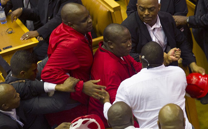 FILE: EFF leader Julius Malema (C) and members of his party clash with security forces. Captain Walter Prins is seen in the black suit manhandling Malema during the Sona on February 12, 2015. Picture: AFP.