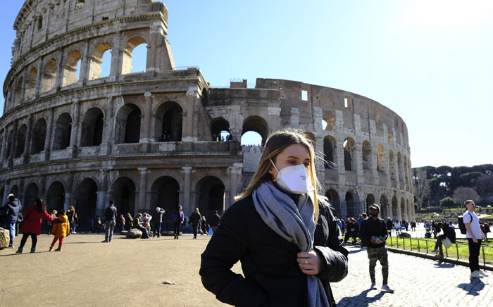 FILE: A tourist wearing a protective respiratory mask walks outside the Coliseum in downtown Rome on 28 February 2020 amid fears of COVID-19 epidemic. Picture: AFP