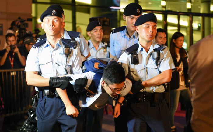 Hong Kong's youngest lawmaker and former Umbrella Movement leader Nathan Law is detained by police after he and other demonstrators staged a sit-in protest at the Golden Bauhinia statue, given to Hong Kong by China to mark the 1997 handover, in front of the Convention and Exhibition Centre in Hong Kong on June 28, 2017. Picture: AFP.