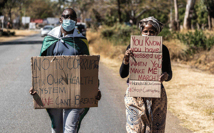 A man and a woman hold placards during an anti-corruption protest march along Borrowdale road, on 31 July 2020 in Harare. Picture: AFP