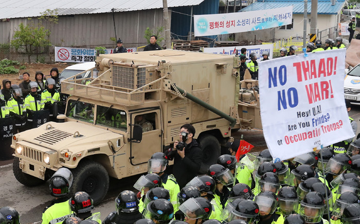 Protesters and police stand by as trailers carrying US THAAD missile defence equipment enter a deployment site in Seongju, early on 26 April 2017. Picture: AFP
