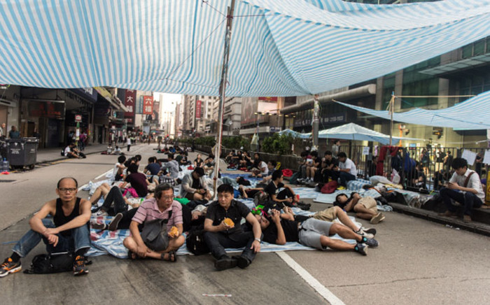 FILE: Commuters eat their breakfast as pro-democracy protesters sleep in the district of Mong Kok in Hong Kong. Picture: AFP.