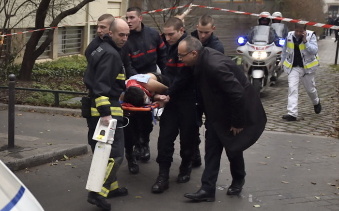 A victim is evacuated on a stretcher on 7 January, 2015 after armed gunmen stormed the offices of the French satirical newspaper Charlie Hebdo in Paris, leaving at least 11 people dead. Picture: AFP.