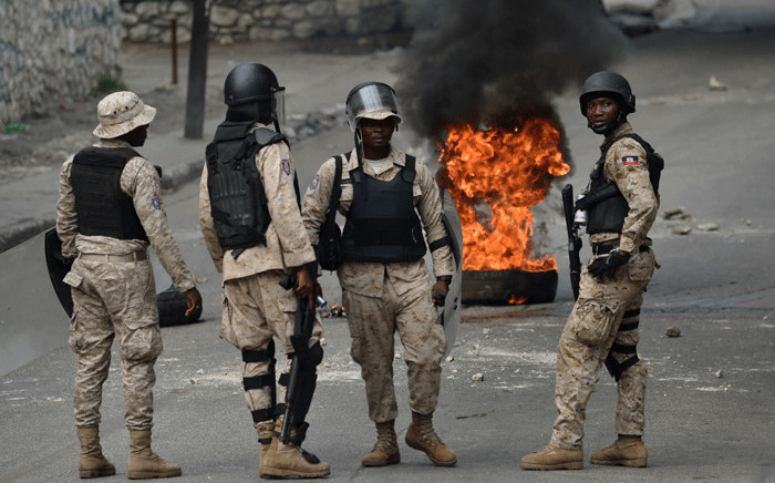 Members of the Haitian police look on during a protest against the remobilisation of the army and angry at a senatorial report that investigated the Petrocaribe funds between 2008 and 2016, after the report said there was embezzlement of public funds, in Port-au-Prince, on 18 November, 2017. Picture: AFP.