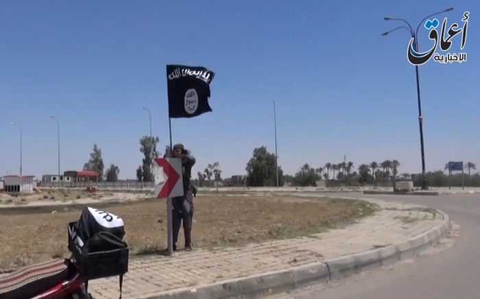 An image grab from a video posted 18 May, 2015 allegedly shows an Isis fighter hanging a flag of the group in a street of Ramadi, Iraq. Picture: AFP/HO/Aamaq.