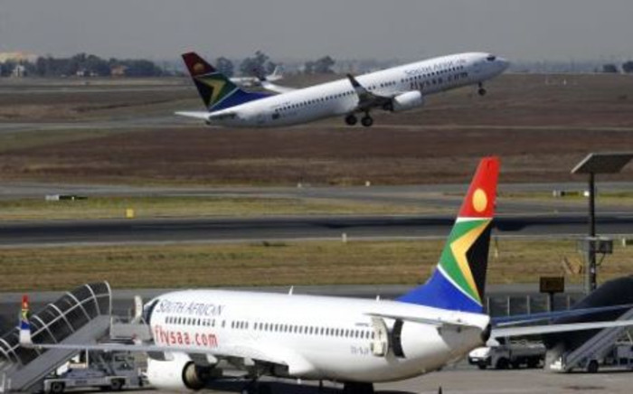 FILE: A South African Airways flight takes off as another one is parked in a bay on the tarmac at OR Tambo International airport in Johannesburg. Picture: AFP
