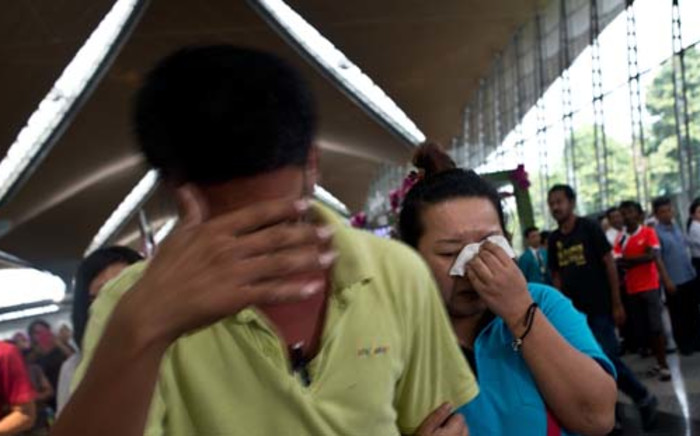A woman (R) breaks down while leaving the reception centre for families and friends after an airliner went missing at the Kuala Lumpur International Airport on March 8, 2014. Picture: AFP.
