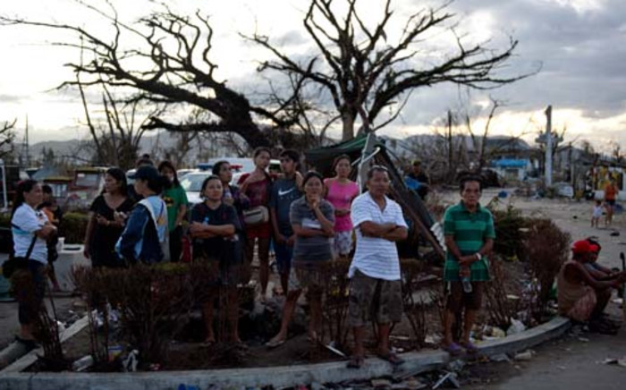 People stand on a corner at the airport watching aid flights land in Tacloban on November 16, 2013. Picture: AFP. 