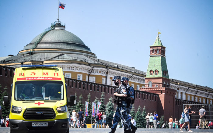 FILE: Russian National Guard servicemen wearing face masks walk along Red Square past an ambulance in central Moscow on 18 June 2021. Picture: Alexander NEMENOV/AFP
