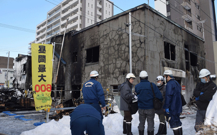 Policemen and firefighters check the ruins of a fire at a residence for elderly people in Sapporo, northern Japan, on 1 February, 2018. Picture: AFP