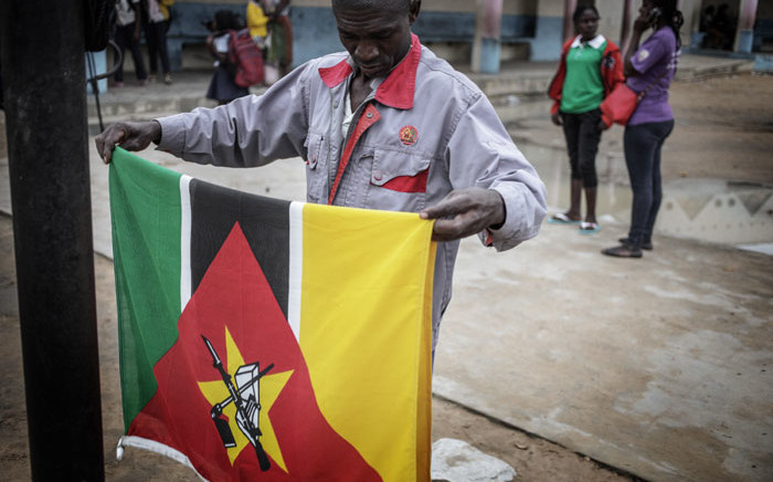 FILE: A school janitor folds the Mozambican national flag at sunset inside a Public School on 4 July, 2018 in Nacala, Mozambique. Picture: AFP
