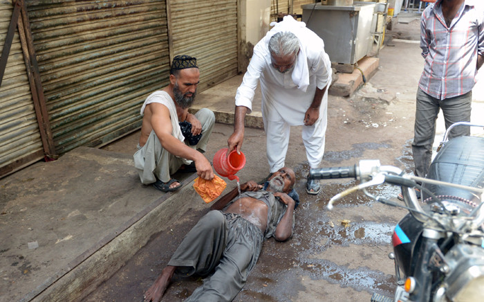 A Pakistani resident helps a heatstroke victim at a market area during a heatwave in Karachi on 23 June, 2015. Picture: AFP.