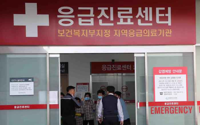 In this picture taken on 21 January 2020, cleaning workers in uniforms wear face masks next to a notice on preventing infection at a hospital, where a Chinese woman who was confirmed to have the new coronavirus strain is isolated, in Incheon. Picture: AFP