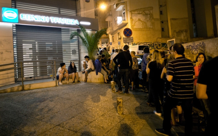 FILE: People queue in front of an ATM to withdraw cash from a National Bank of Greece in central Athens on 28 June 2015. Picture: AFP.