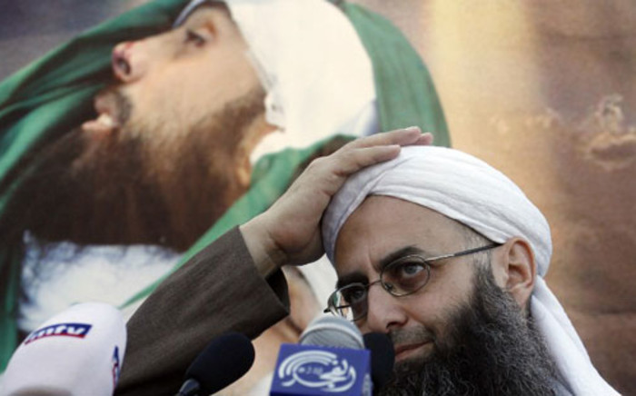 Lebanese Salafist figure Sheikh Ahmad al-Assir gestures in front of a picture of slain supporter Lubnan al-Azzi during a protest against the Syrian regime in the southern Lebanese city of Sidon on 2 December 2012. Picture: AFP.