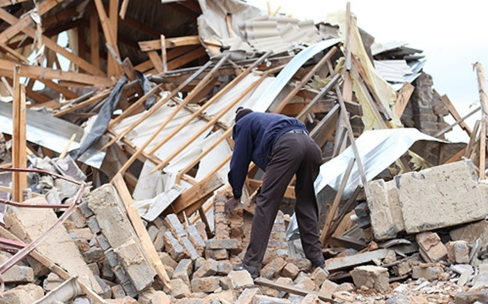 FILE: A Lenasia resident picks up bricks from his demolished house. Picture: EWN.