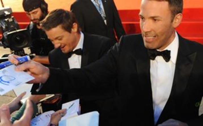 US film director Ben Affleck (R) and actor Jeremy Renner sign autographs. Picture: AFP.