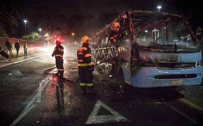Firefighters extinguish a Jammie Shuttle that was torched by protesting #RhodesMustFall students at UCT. Picture: Thomas Holder/EWN