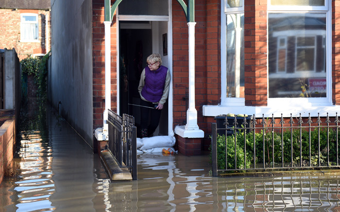 FILE: A woman looks out from a flooded property adjacent to the River Foss which burst its banks in York, northern England, on 27 December, 2015. Picture: AFP.