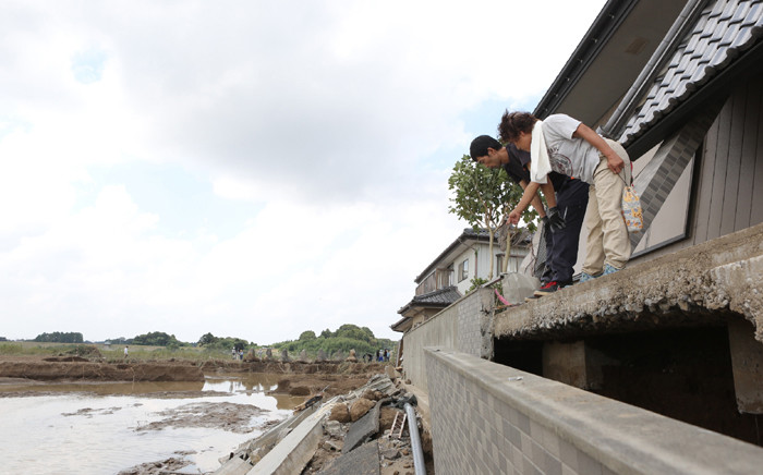 Local residents check a collapsed embankment following the floods from their residence in the city of Joso, Ibaraki prefecture on September 12, 2015. Picture: AFP.