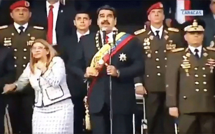 Screengrab taken from a handout video released by Venezuelan Television showing Venezuelan President Nicolas Maduro, his wife Cilia Flores and military authorities reacting to a loud band during a ceremony to celebrate the 81st anniversary of the National Guard in Caracas on 4 August, 2018. Picture: AFP