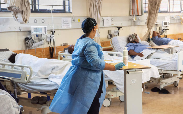FILE: A hospital worker walks amongst patients in the COVID-19 ward at Khayelitsha Hospital, about 35km from the centre of Cape Town, on 29 December 2020. The patents in this ward are not critically serious, but do require oxygen and to lie down. Picture: Rodger Bosch/AFP.