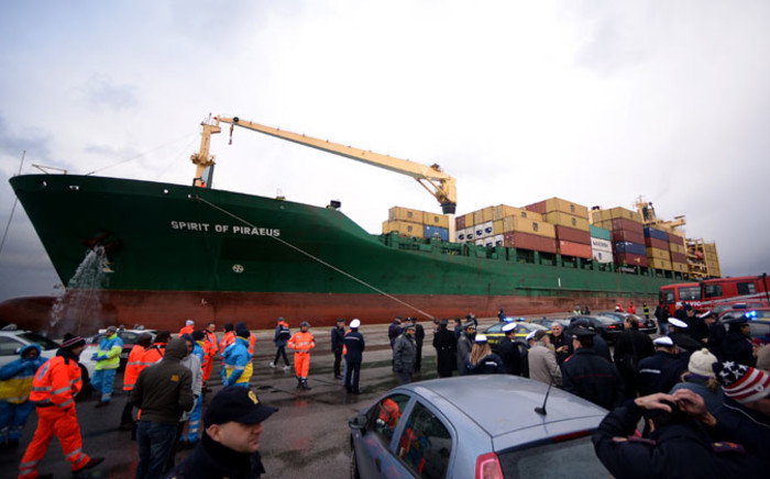 The Singapore-flagged cargo container ship Spirit of Piraeus, carrying 49 passengers evacuated from the ferry Norman Atlantic, arrives in the harbour of Bari on 29 December, 2014, as Italian advanced rescue personnel and police wait on the quay. Picture: AFP.