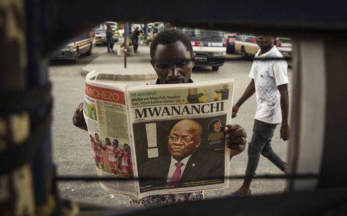 A man reads a newspaper with a headline announcing the death of Tanzania's President John Magufuli in Dar es Salaam, on 18 March 2021. Picture: AFP.