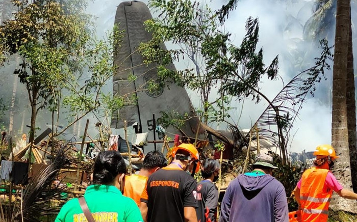 In this handout photo taken on July 4, 2021 and received from the Philippine military Joint Task Force-Sulu (JTF-Sulu), rescue workers arrive as smoke billows from the wreckage of a Philippine Airforce C-130 transport plane after it crashed near the airport in Jolo town, Sulu province on the southern island of Mindanao. Picture: AFP: 
