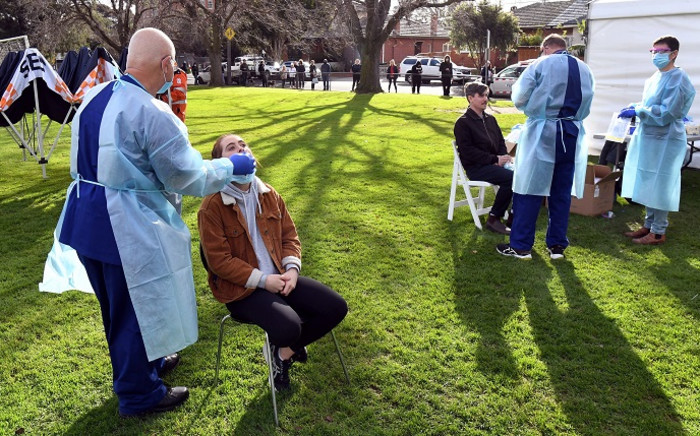 Interstate health workers from Adelaide in South Australia take a swab as people queue during COVID-19 coronavirus testing in a park in the Melbourne suburb of Brunswick West on July 2, 2020. Picture: AFP
