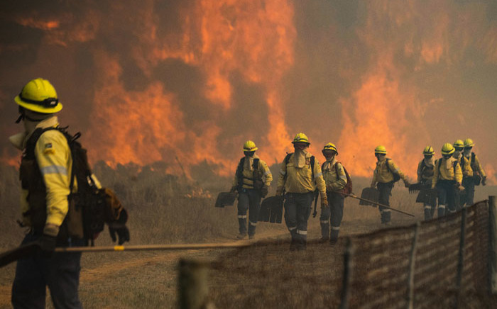 Firefighters leave an area where the flames become too aggressive, as a forest fire burns out of control on the foothills of Table Mountain, above the University of Cape Town, in Cape Town, on 18 April 2021. Picture: Rodger Bosch/AFP