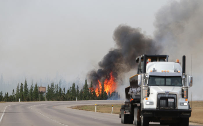 FILE: Flames rise off Highway 63 outside Fort McMurray, where raging forest fires have forced more than 88,000 from their homes. Pictures: AFP.