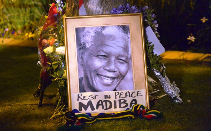 FILE: A file photo taken on 6 December, 2013 shows a framed image of former South African president Nelson Mandela as people pay tributes following his death, in Johannesburg. Picture: AFP.