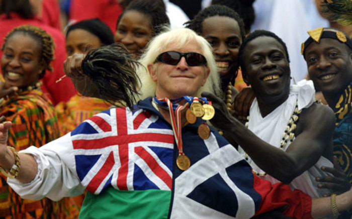 File picture taken on June 4, 2002 of Jimmy Savile, a television and radio celeberity joining in with people representing Commonwealth countries wearing their tradional dress crowd into the forecourt of Buckingham Palace during the Golden Jubilee celebrations in London. Picture: AFP.