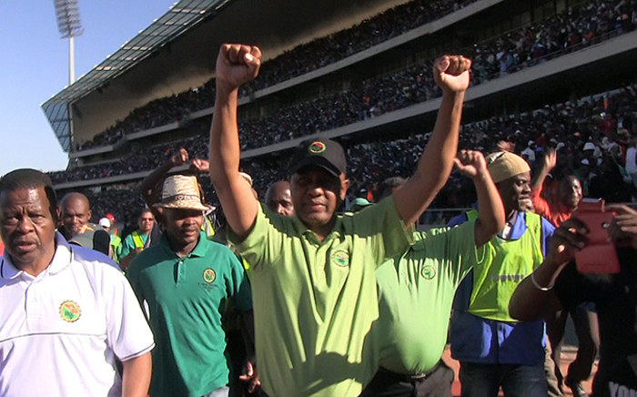 The Association of Mineworkers and Construction Union (Amcu) leader Joseph Mathunjwa raises his hands triumphantly in the Royal Bafokeng stadium near Rustenburg as miners agree to sign a wage agreement which ended the longest strike in South African history on 23 June 2014. Picture: Reinart Toerien/EWN