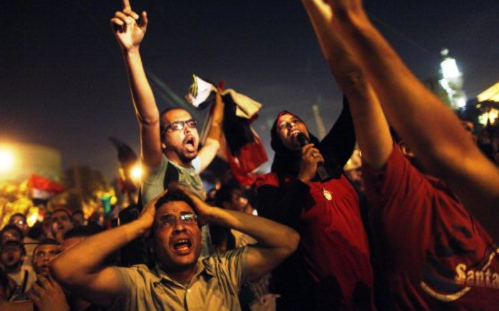 Egyptian protesters calling for the ousting of President Mohamed Morsi react as they watch his speech on a screen in a street leading to the presidential palace early in Cairo on 3 July, 2013. Picture: AFP/ Mahmud Khaled