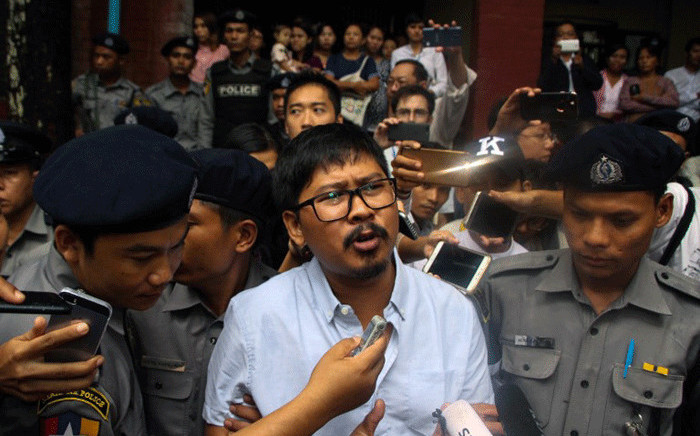 Detained Myanmar journalist Wa Lone (C) speaks to reporters as he is escorted by police from a courthouse following his ongoing pre-trial hearing in Yangon on 9 July, 2018. Picture: AFP.