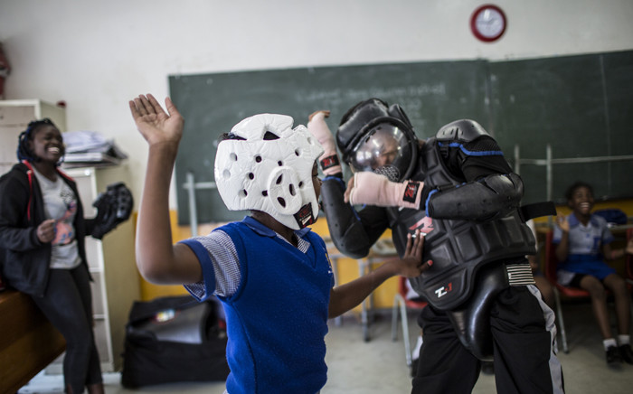 Girls practice self-defence methods on an instructor dressed in protective gear during a session with NGO Action Breaks Silence (ABS) called 'Empowerment through self-defence for women and girls' which aims to create a world free from fear of gender-based violence, on 10 October 2018 at Mbuyisa Makhubu Primary School in Soweto. Picture: AFP.