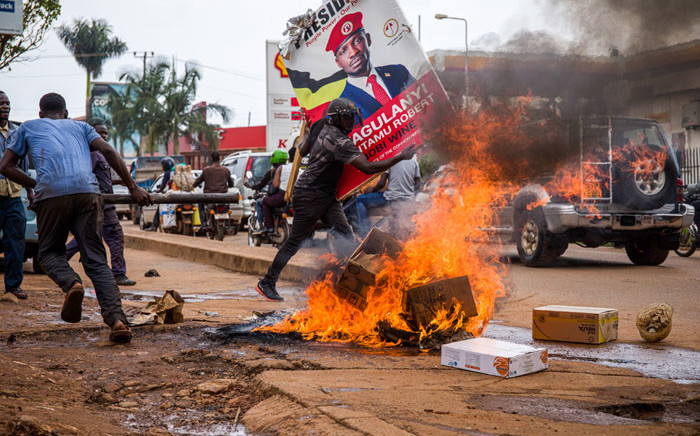 A supporter of Ugandan musician turned politician Robert Kyagulanyi, also known as Bobi Wine, carries his poster as they protest on a street against the arrest of Kyagulanyi during his presidential rally in Kampala, Uganda, on 18 November 2020. Picture: AFP