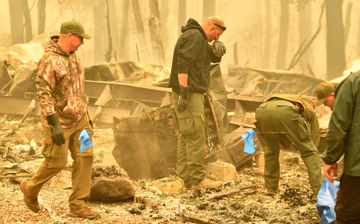 Yuba and Butte County Sheriff officers react as they discover a body at a burned out residence after the camp fire tore through the area in Paradise, California on 10 November 2018. Picture: AFP