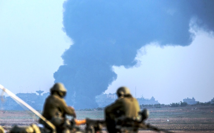 FILE: Israeli soldiers sitting on a tank hold their position on the Israeli side of the border with the Gaza Strip on 22 July as smoke billows from the coastal Palestinian enclave. Picture: AFP.