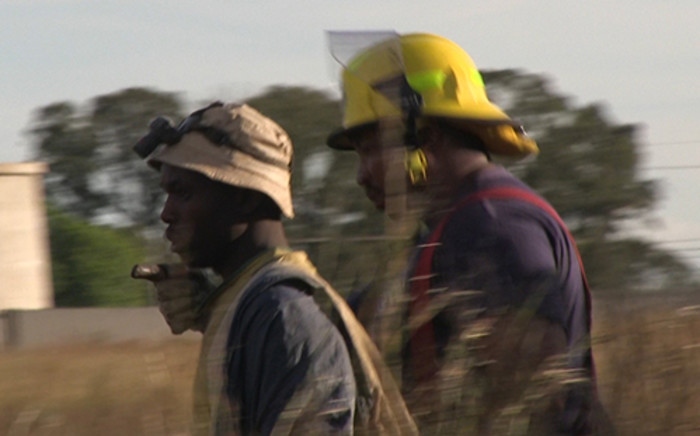 One of the eleven trapped miners is escorted by a rescue worker after being pulled above ground having spent a night underground in an illegal mine in Benoni on 16 February 2014. Picture: Reinart Toerien/EWN.