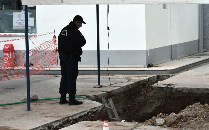 A policeman looks at the hole where an unexploded bomb dating to the World War II was found during work to expand a gas station’s underground tanks in Thessaloniki. Picture: AFP.