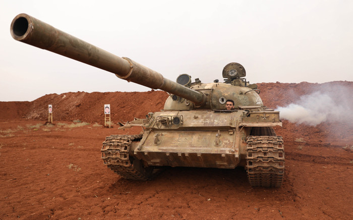 FILE: A Syrian rebel-fighter from the National Liberation Front (NLF) secures a tank, part of heavy weapons and equipment withdrawn on 8 October 2018 from a planned buffer zone around Idlib in one of the group's rear positions in a rebel-held area in the south-western Syrian province. Picture: AFP.