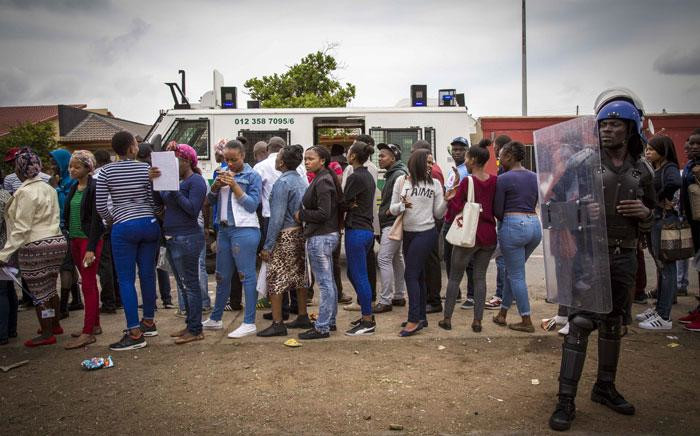 TUT wait to board a bus under the watchful gaze of security personnel. Picture: Thomas Holder/EWN