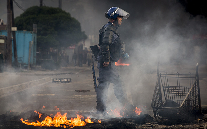 FILE: A Public Order Police officer walks passed a pile of burning debris used as a roadblock during riots. Picture: Thomas Holder/EWN