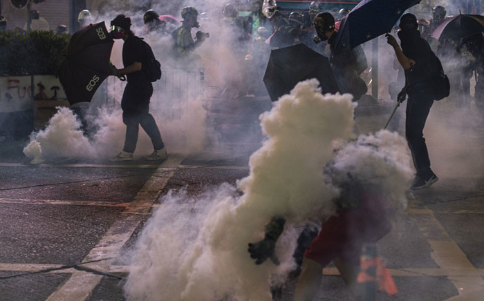 FILE: Masked protesters use umbrellas as Hong Kong police fire tear gas during a pro-democracy rally in Kowloon district in Hong Kong on 20 October 2019. Picture: AFP