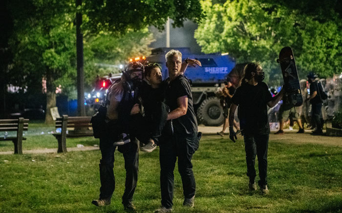 Demonstrators carry a wounded person, during a clash with law enforcement, on 25 August 2020 in Kenosha, Wisconsin. Picture: AFP